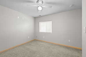 Carpeted room featuring a ceiling fan with integrated lighting, a single window with blinds, light gray wall paint, and light-toned baseboards