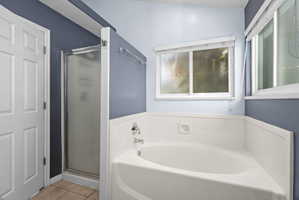 Bathroom featuring a built-in corner soaking tub, separate shower with frosted glass enclosure, and white panel wainscoting