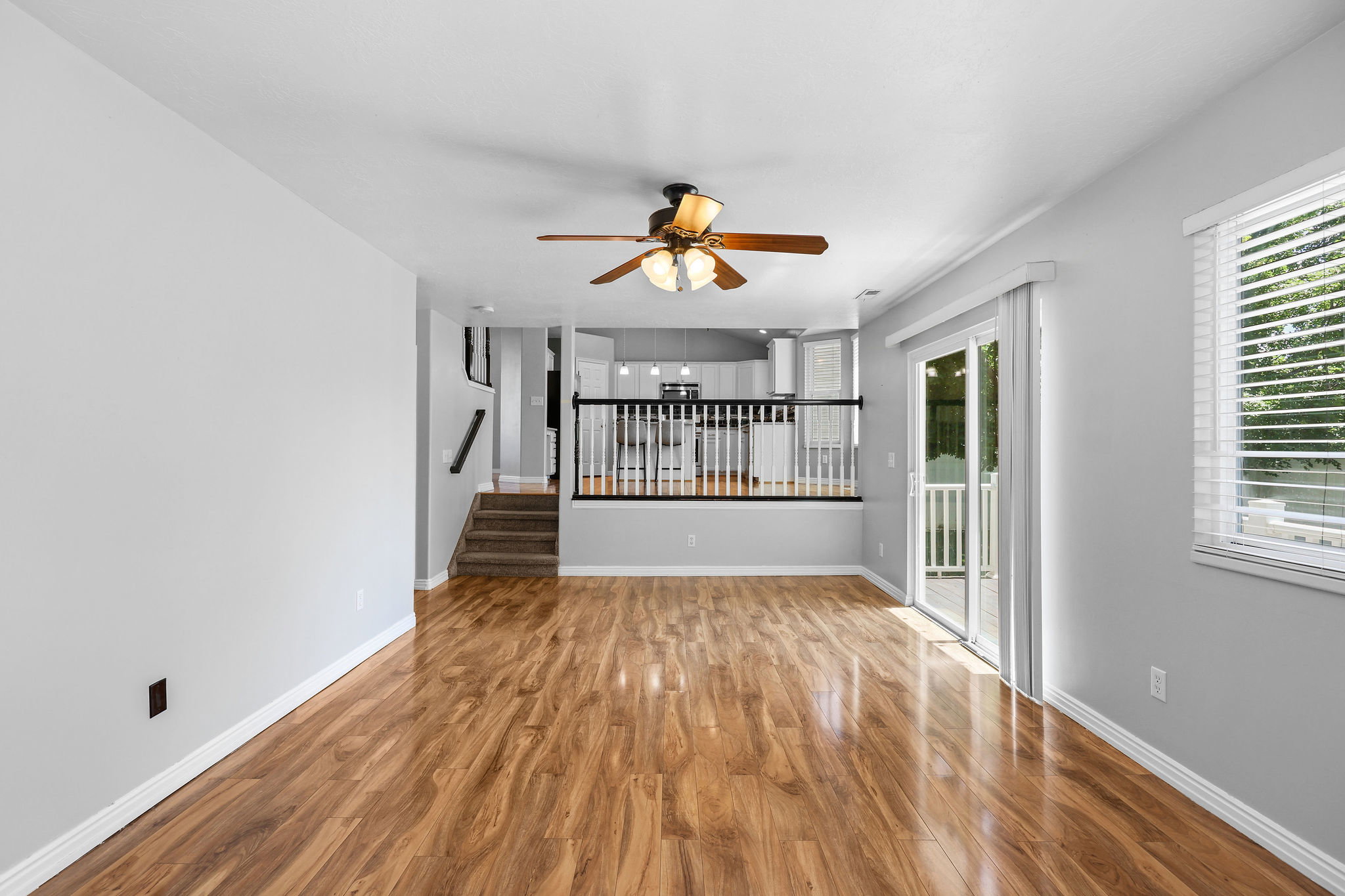 Spacious interior featuring wood-finish flooring, a ceiling fan, and light gray wall tones