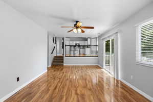 Spacious interior featuring wood-finish flooring, a ceiling fan, and light gray wall tones