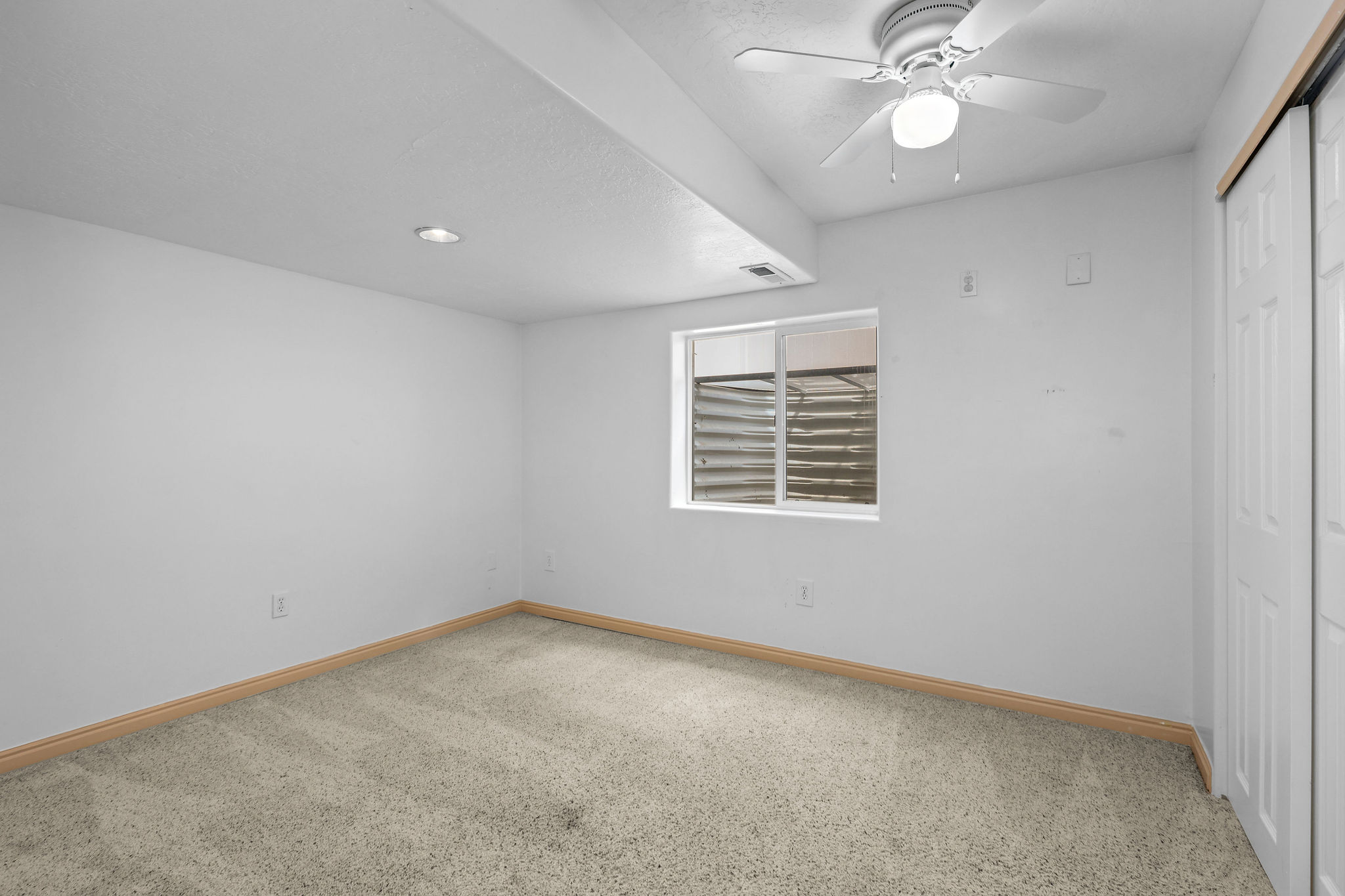 Carpeted room featuring a ceiling fan, recessed lighting, a window, and a white bi-fold closet