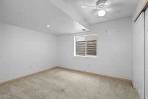 Carpeted room featuring a ceiling fan, recessed lighting, a window, and a white bi-fold closet