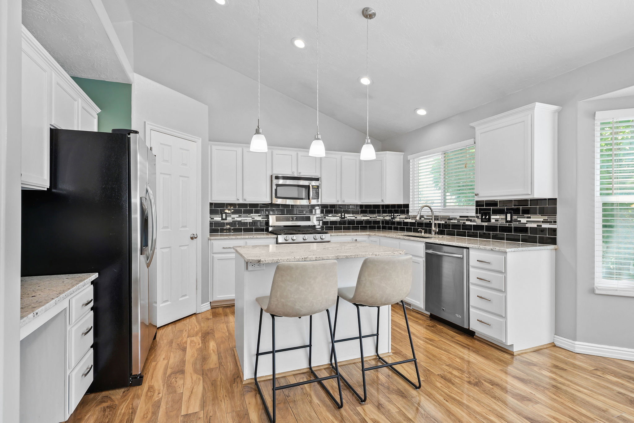 Kitchen featuring white cabinetry, wood-finish flooring, and a stone-finish island with pendant lighting