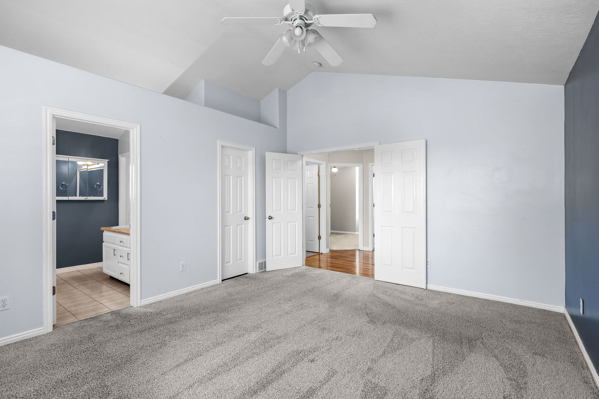 Spacious room with vaulted ceilings and a ceiling fan