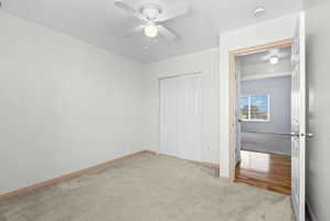 Carpeted room featuring a ceiling fan with light fixture and bifold closet doors