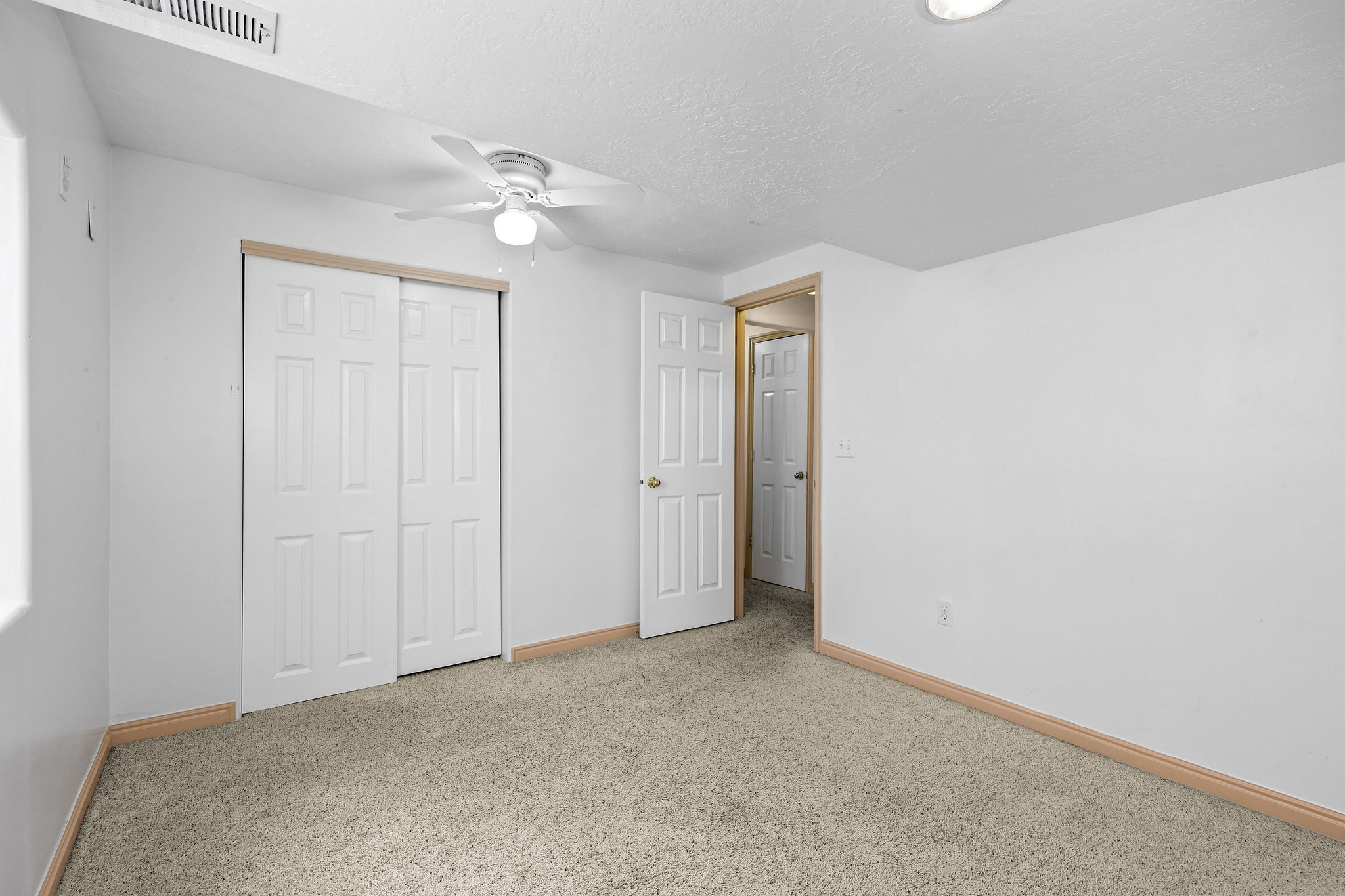Carpeted room with white walls and a ceiling fan