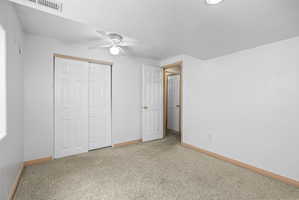 Carpeted room with white walls and a ceiling fan