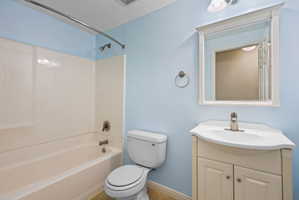 Full bathroom featuring a white tub/shower combination with chrome fixtures, a white toilet, and a vanity with a white countertop and base cabinet