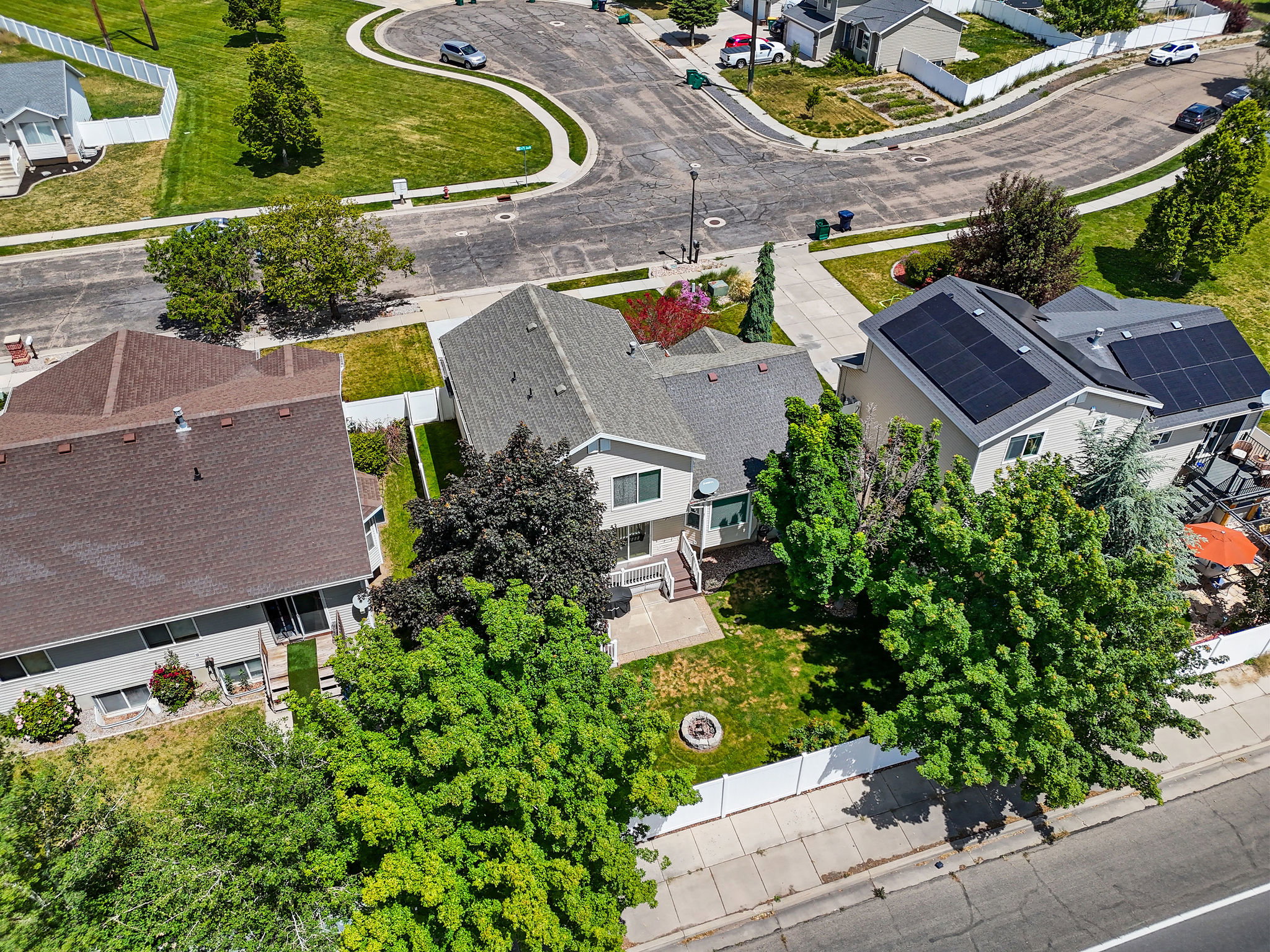 Aerial perspective showcasing a residential property with an expansive backyard featuring a manicured lawn and mature trees