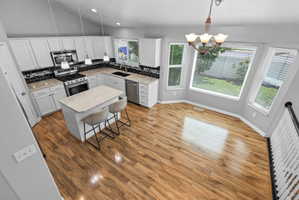 Kitchen and dining area featuring wood-finish flooring, white cabinetry, dark subway tile backsplash, and light-toned countertops