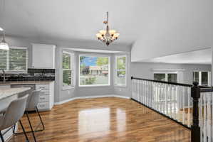 Bright dining area featuring a bay window, wood-finish flooring, and a decorative chandelier