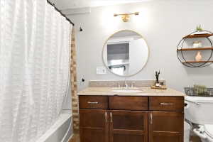 Bathroom featuring a wood-finish vanity with a light-colored countertop and undermount sink