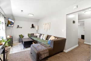 Spacious living area featuring neutral carpeting, a large window with natural light, and recessed lighting