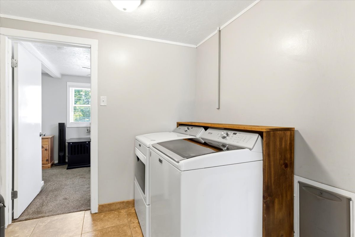 Dedicated laundry area featuring a wood-finish countertop, neutral wall paint, and ceramic tile flooring