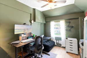 Room with green walls, wood-finish flooring, and a single window with white curtains