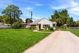 Single-story residence featuring white horizontal siding, dark window shutters, and a light-colored roof