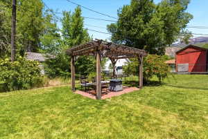 Expansive backyard featuring a wood pergola over a brick patio