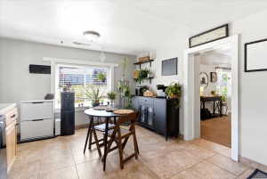 Kitchen dining area featuring neutral tile flooring, a window with blinds, and white trim