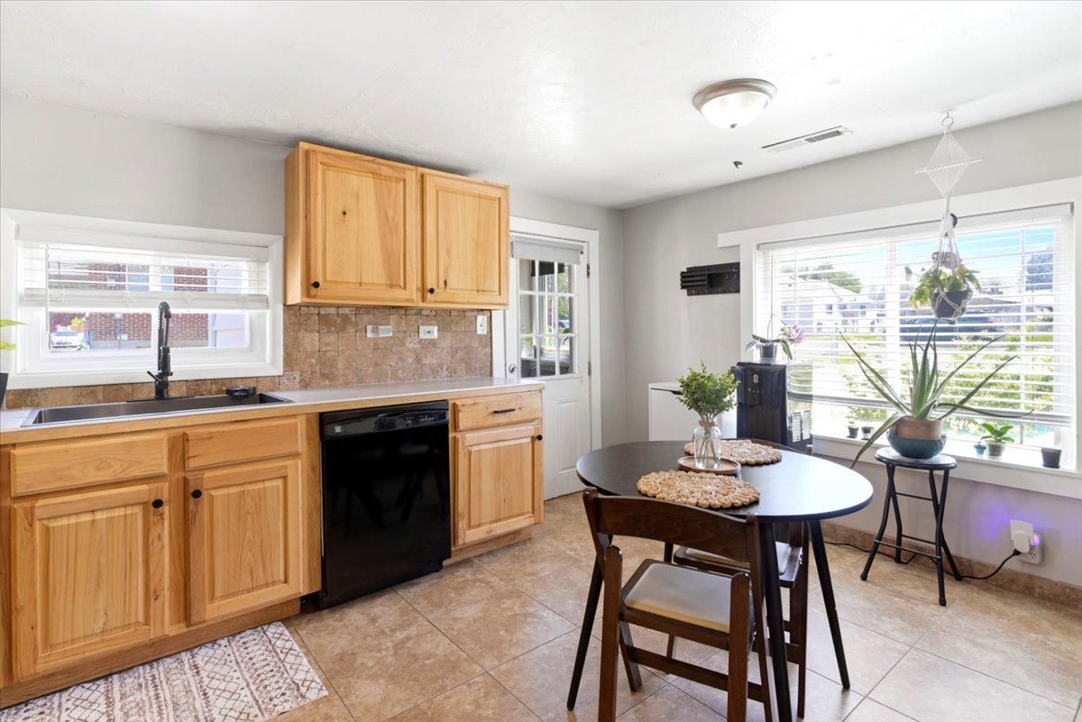 Kitchen featuring natural wood cabinetry, light-toned countertops, a black appliance package, and a tiled backsplash