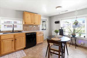 Kitchen featuring natural wood cabinetry, light-toned countertops, a black appliance package, and a tiled backsplash