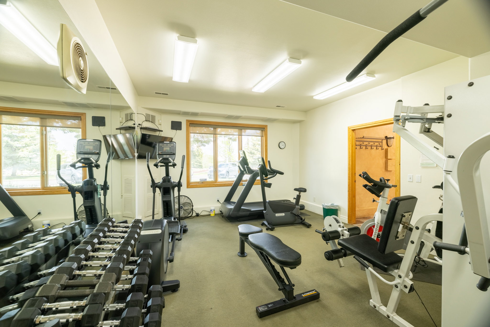 Dedicated fitness room featuring multiple windows with wood trim, recessed lighting, and a neutral wall color