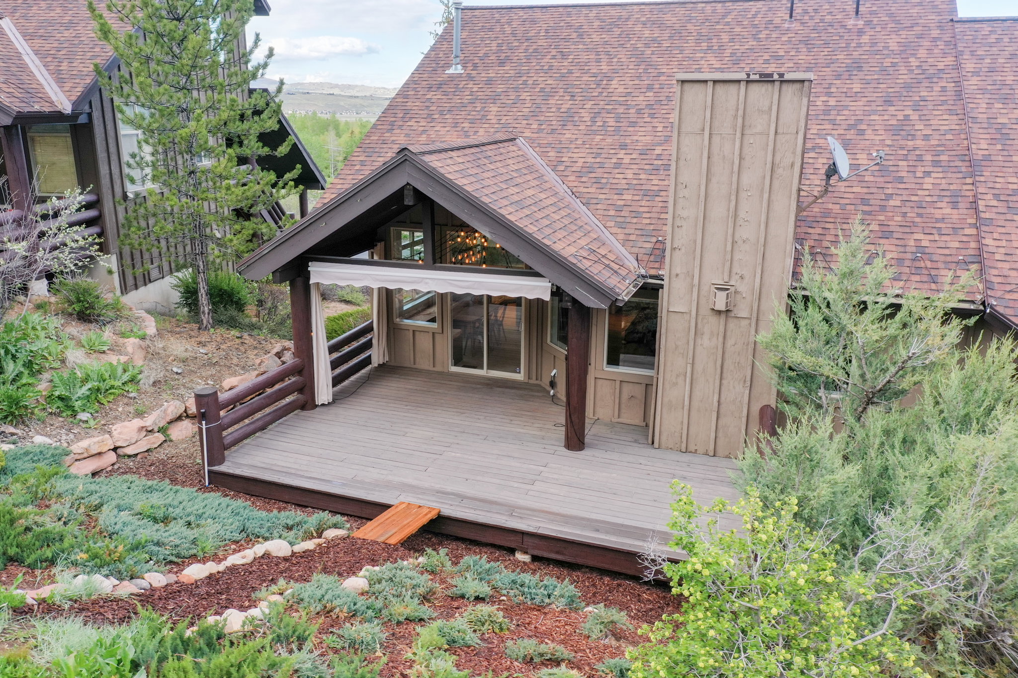 Expansive outdoor deck with a covered portion, featuring wood-finish railing and a sliding glass door entry