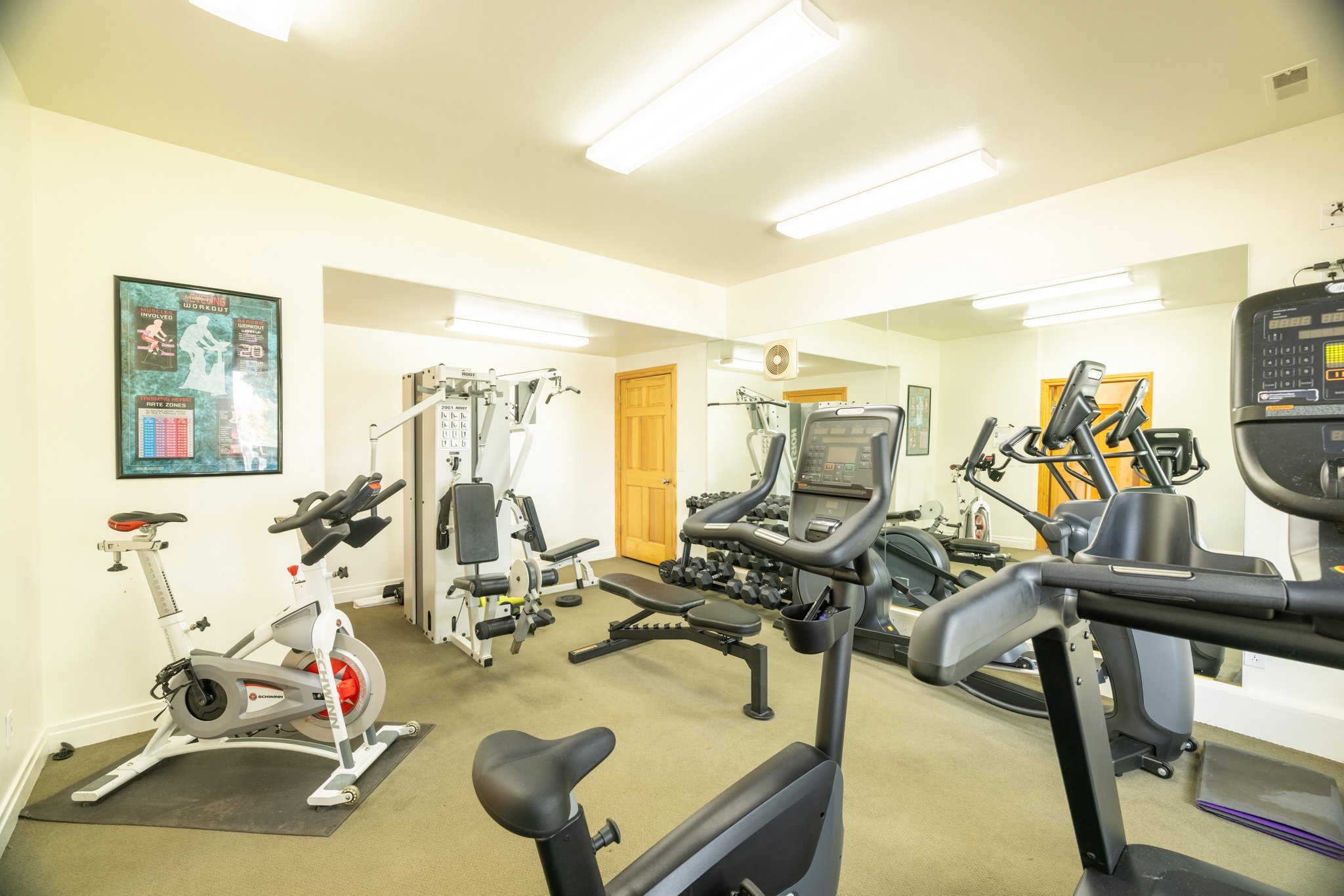 Dedicated fitness space featuring wall-mounted mirrors and recessed lighting