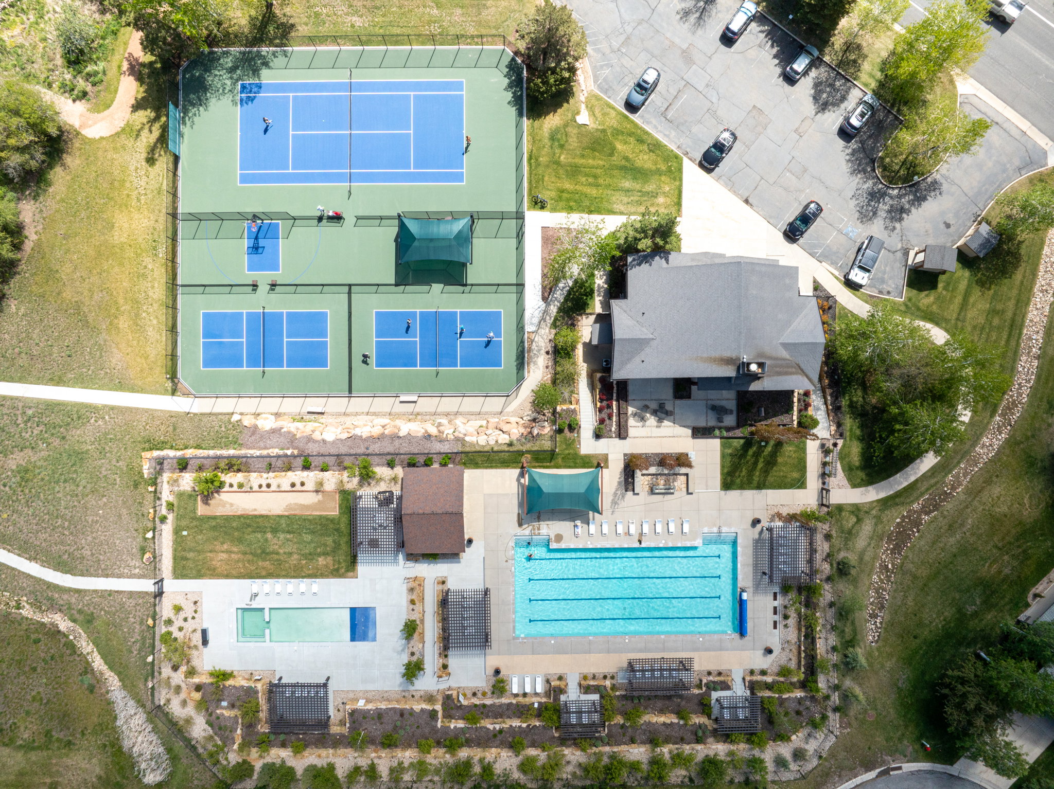 Recreational complex featuring a large swimming pool, a smaller wading pool, and multiple sports courts including tennis, pickleball, and basketball