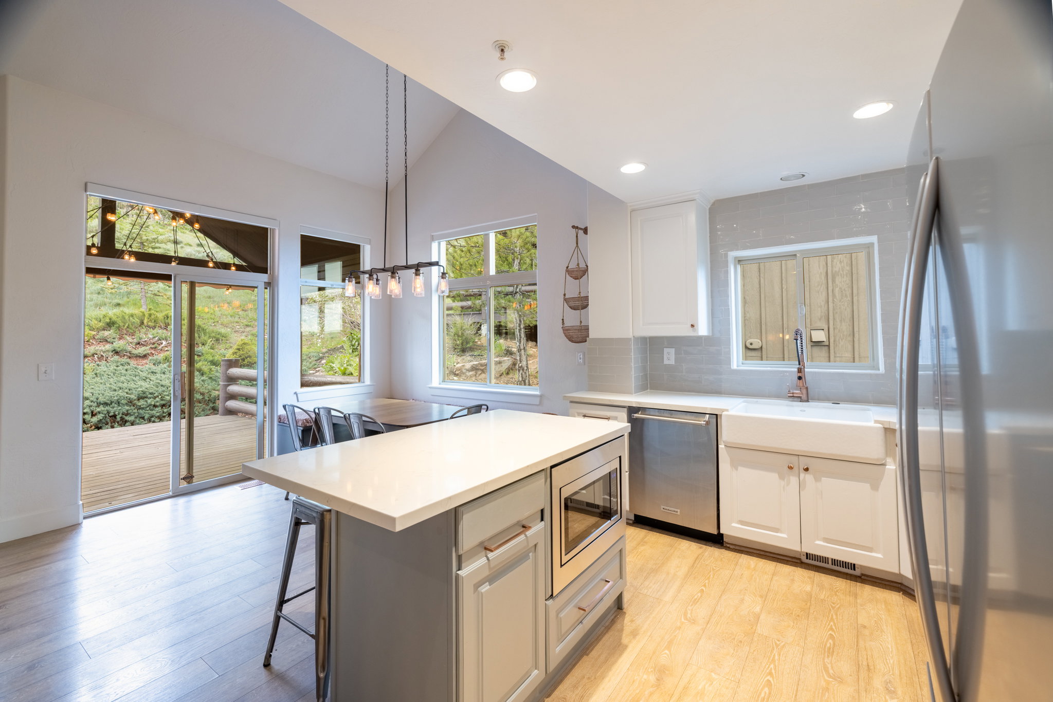 Modern kitchen featuring light wood-finish flooring, white cabinetry, and a large central island with a built-in microwave