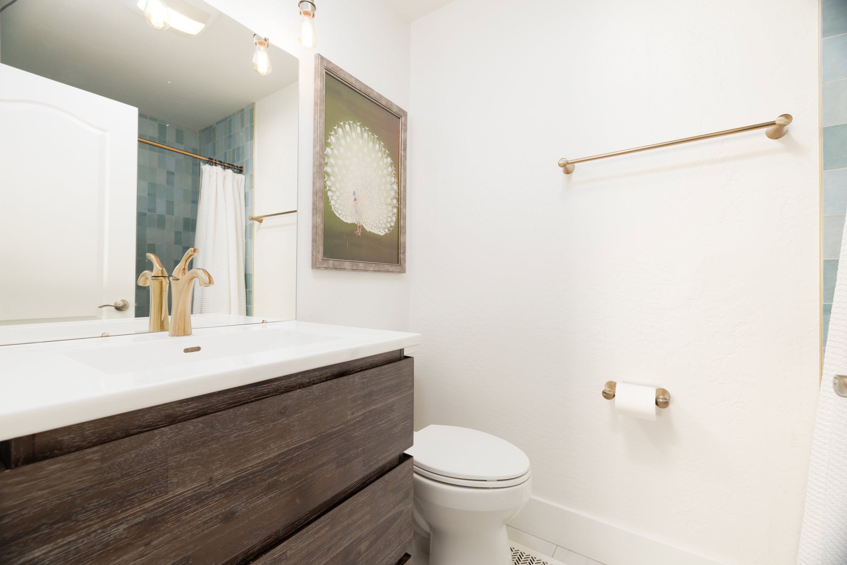 Vanity featuring a white countertop with integrated sink and gold-tone faucet
