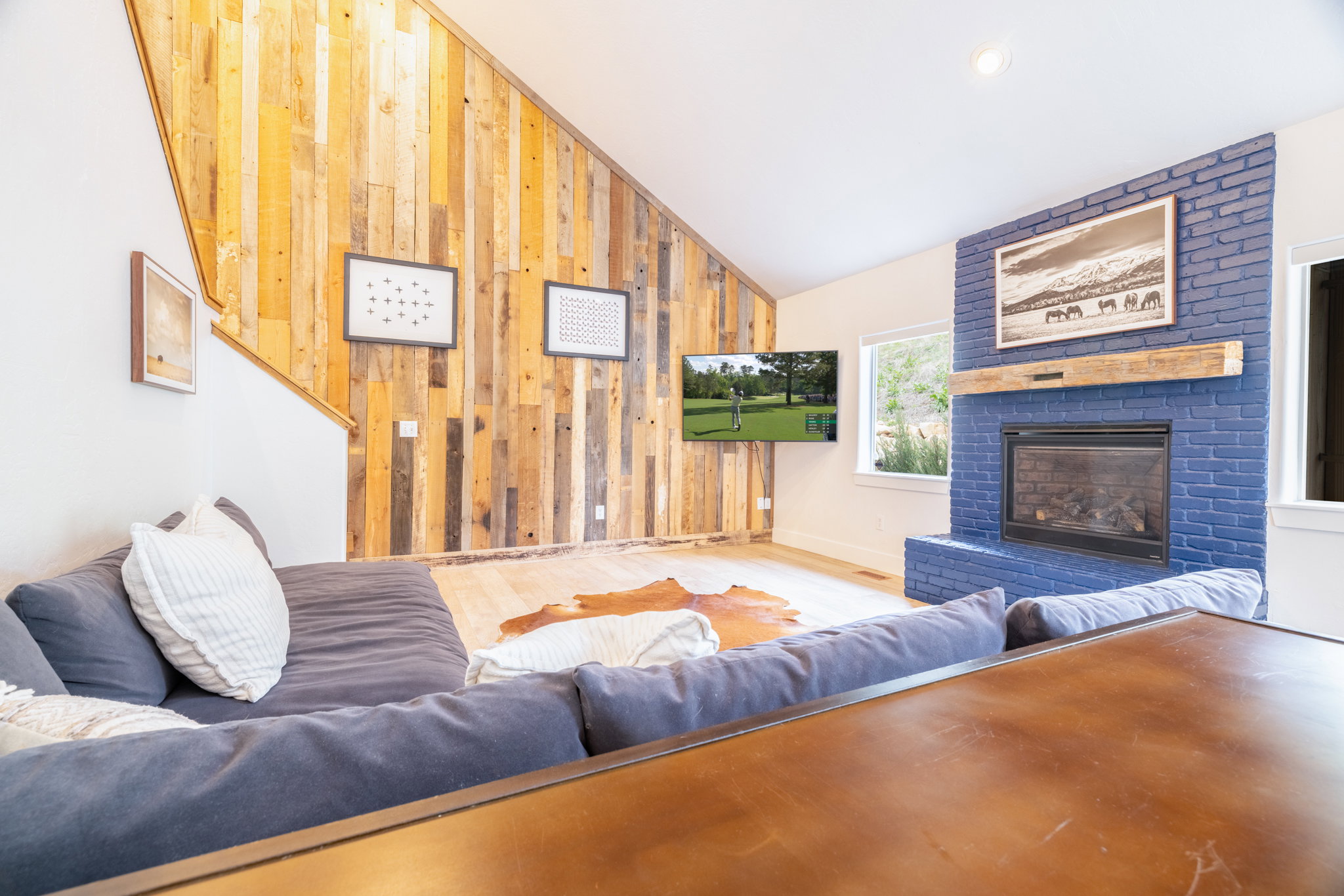 Vaulted ceiling with an accent wall featuring vertical wood-finish paneling