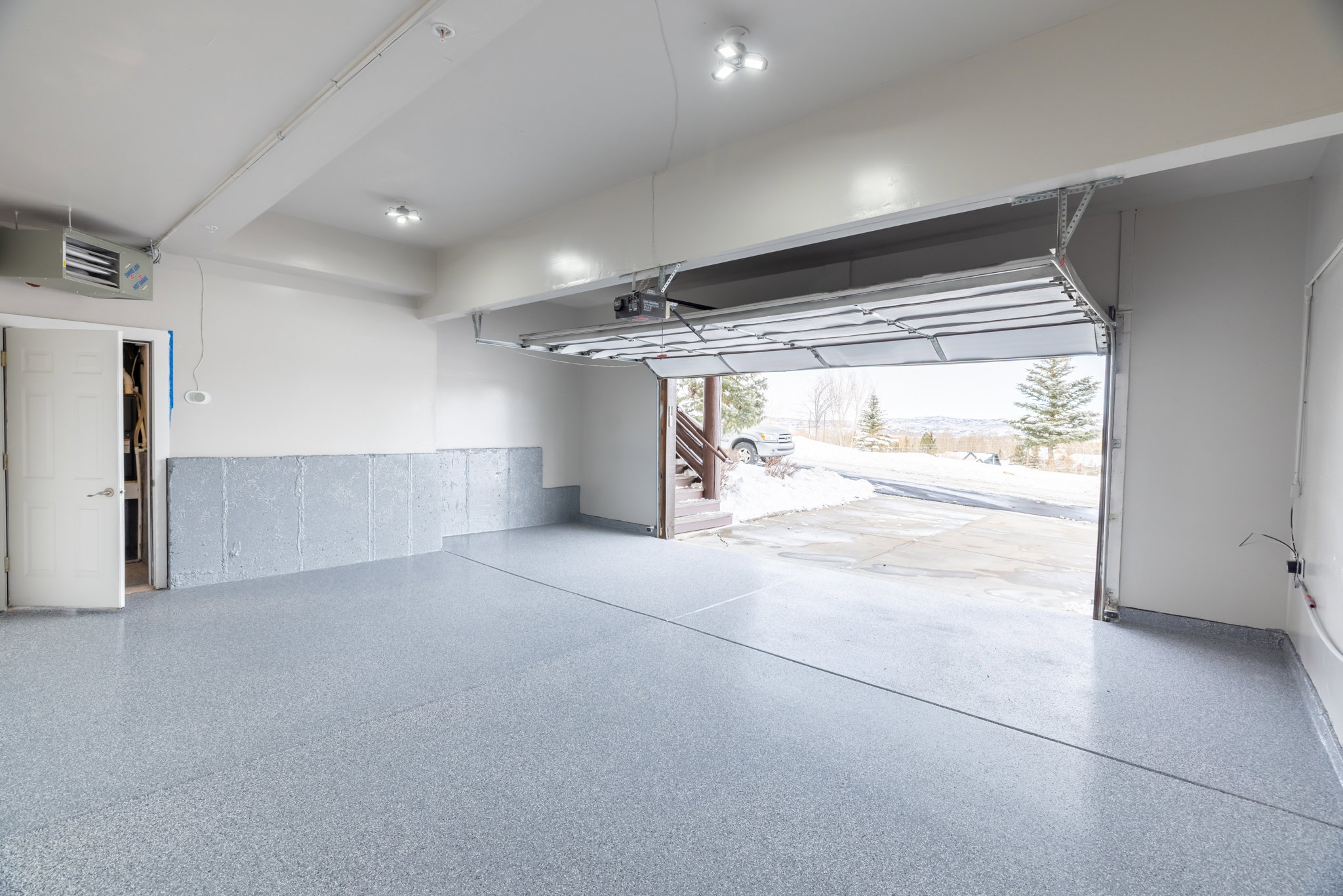 Spacious garage with an epoxy-coated floor, overhead lighting, and an automatic garage door