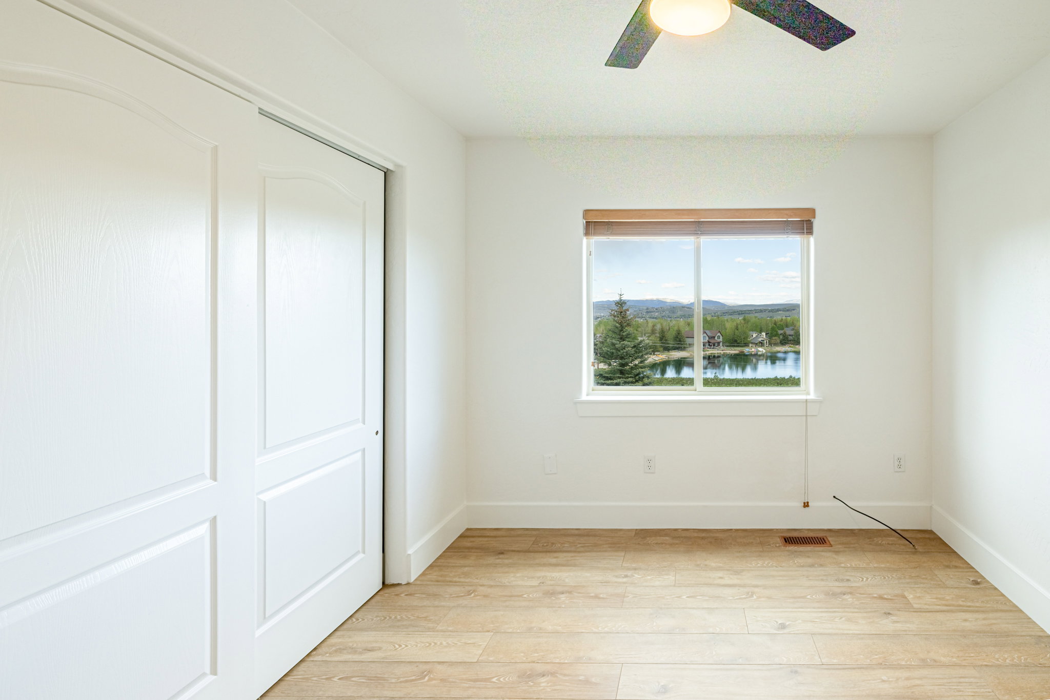 Bright interior space featuring wood-finish flooring, white walls, and a ceiling fan