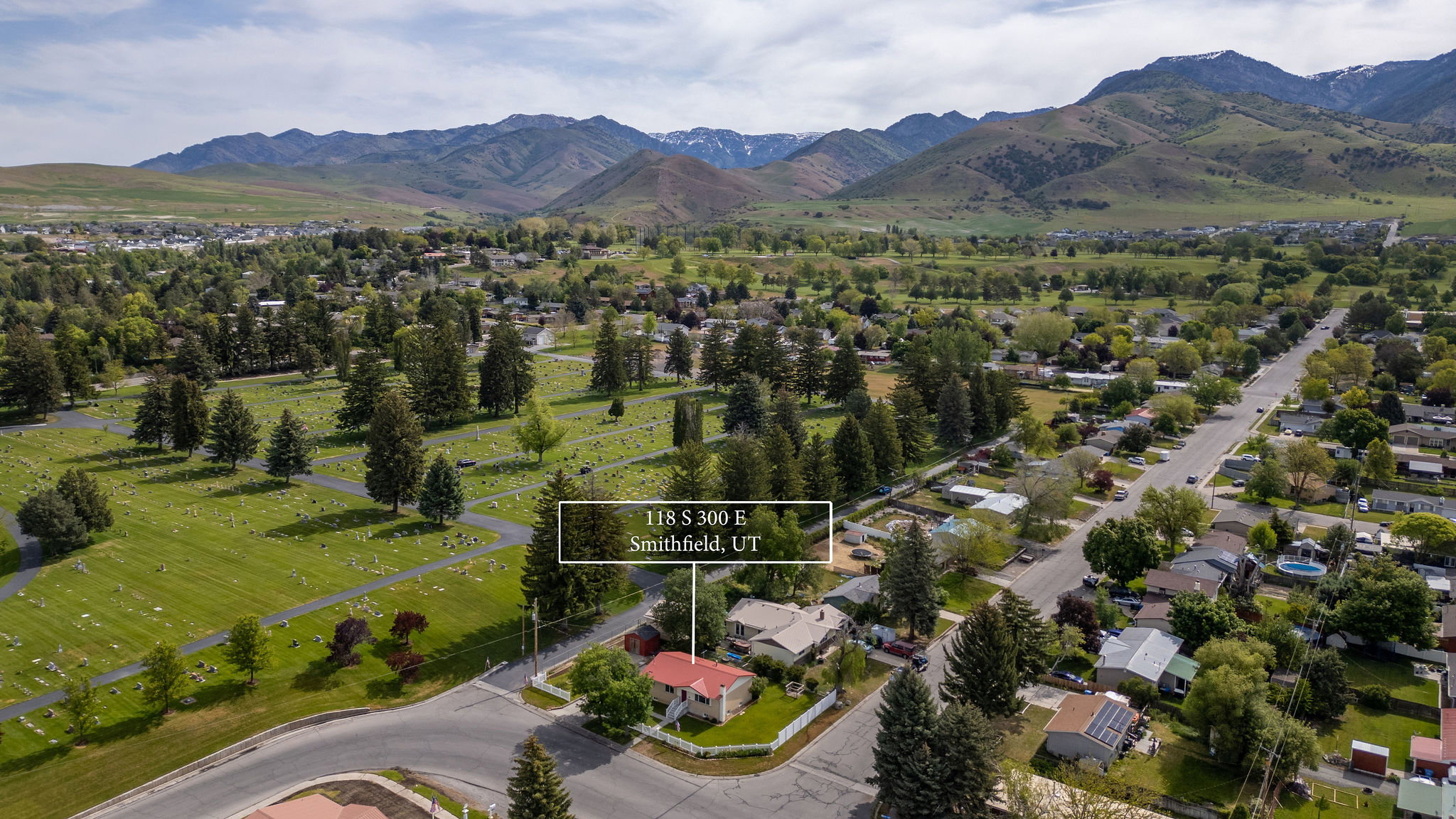 Aerial perspective highlighting a residential property with a red roof, situated on a corner lot