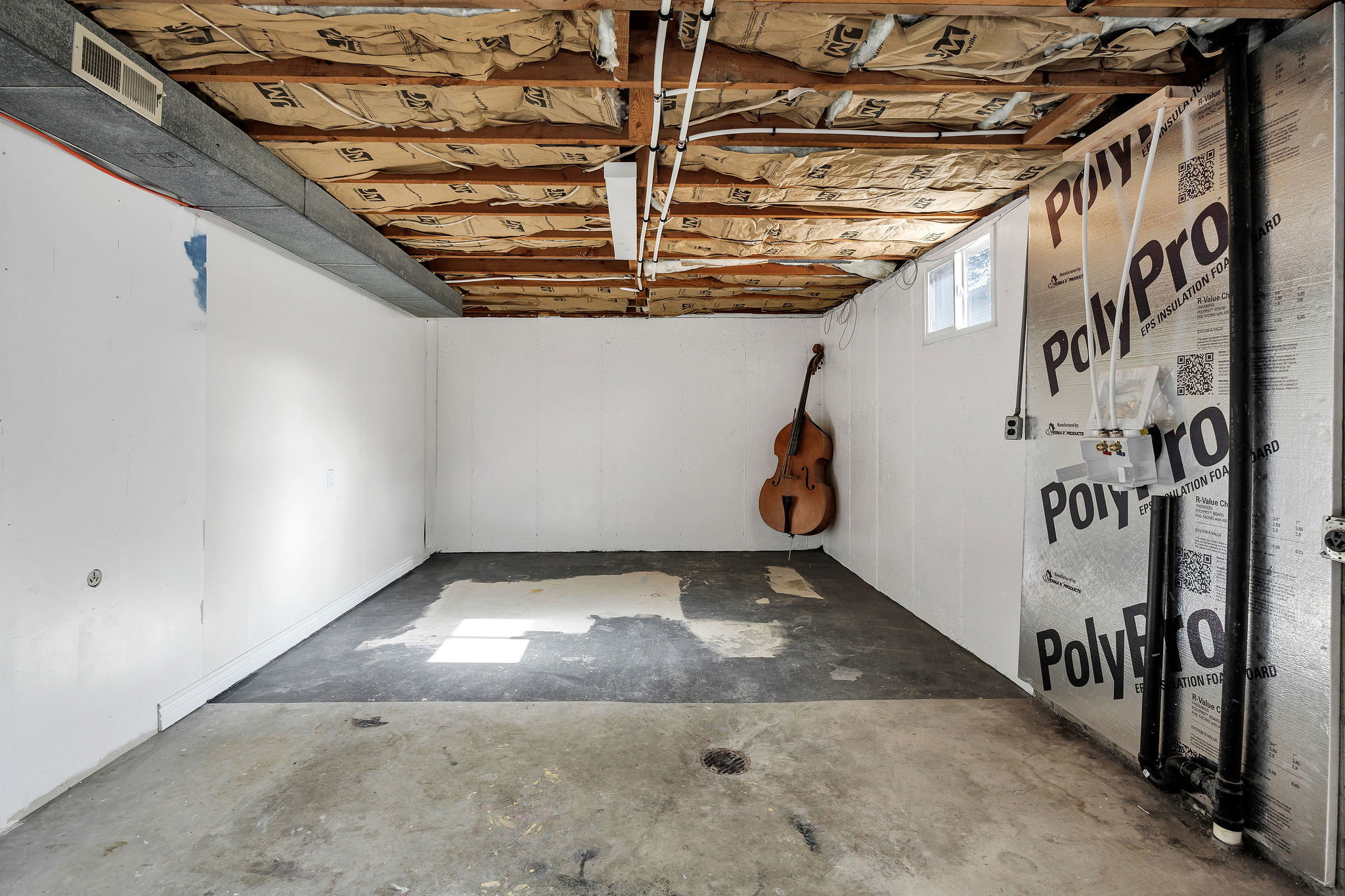 Unfinished basement space featuring exposed ceiling joists, insulation, and concrete flooring