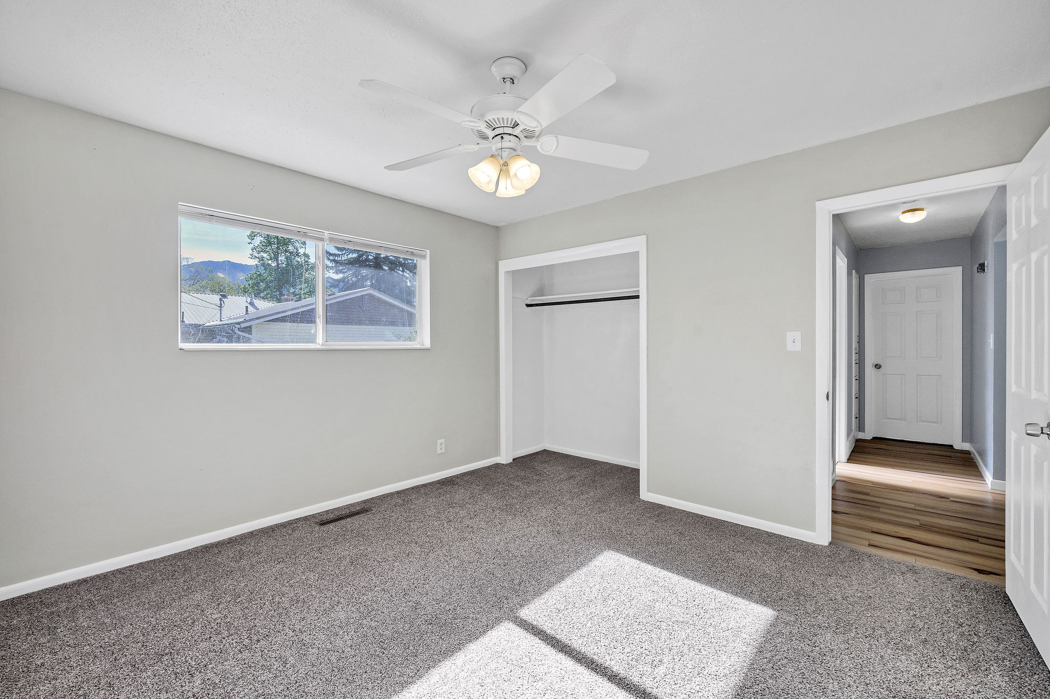 Carpeted room with a ceiling fan, a window, and a built-in closet