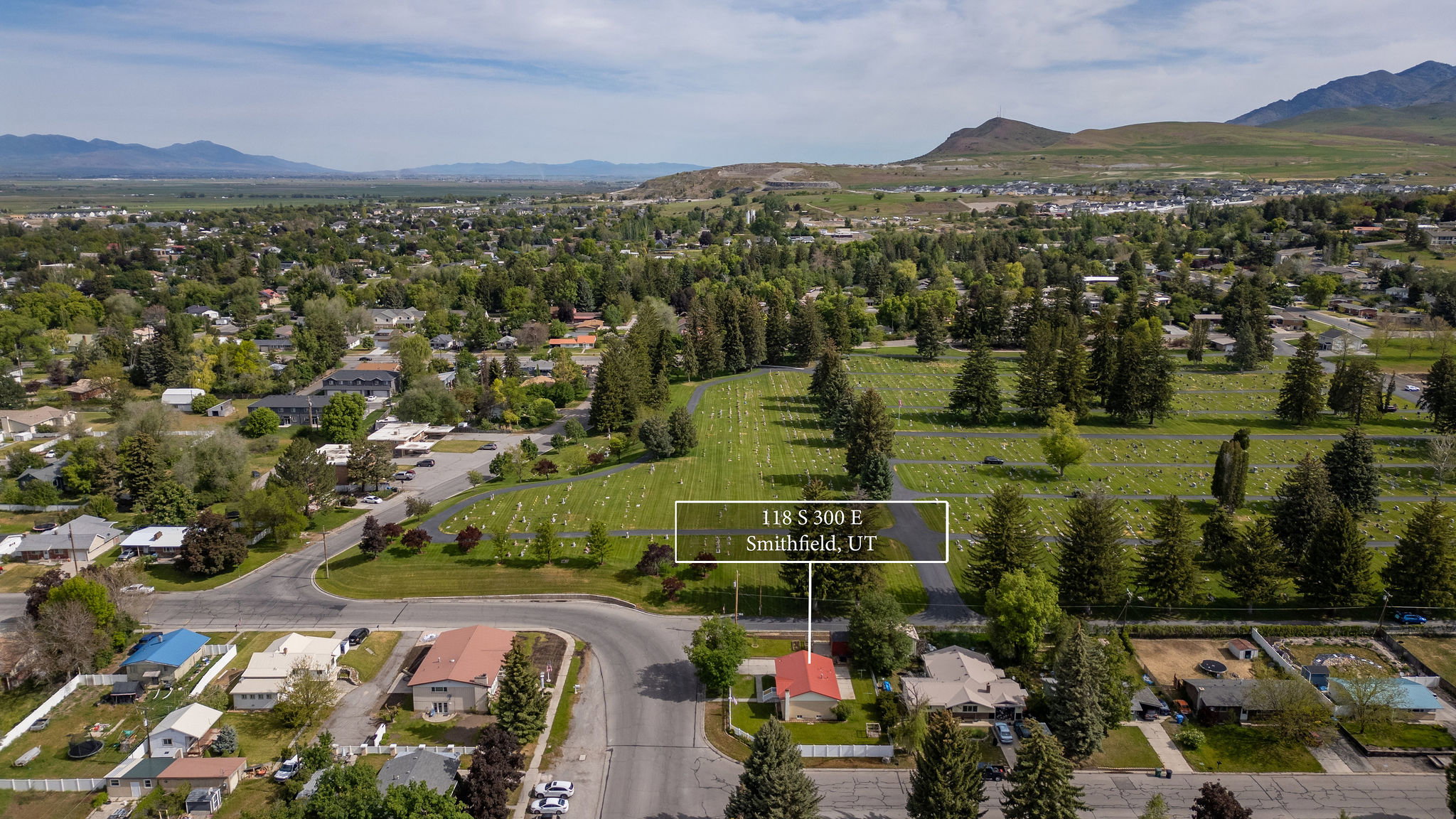 Aerial view showcasing the property within a residential neighborhood with surrounding green spaces and distant mountains