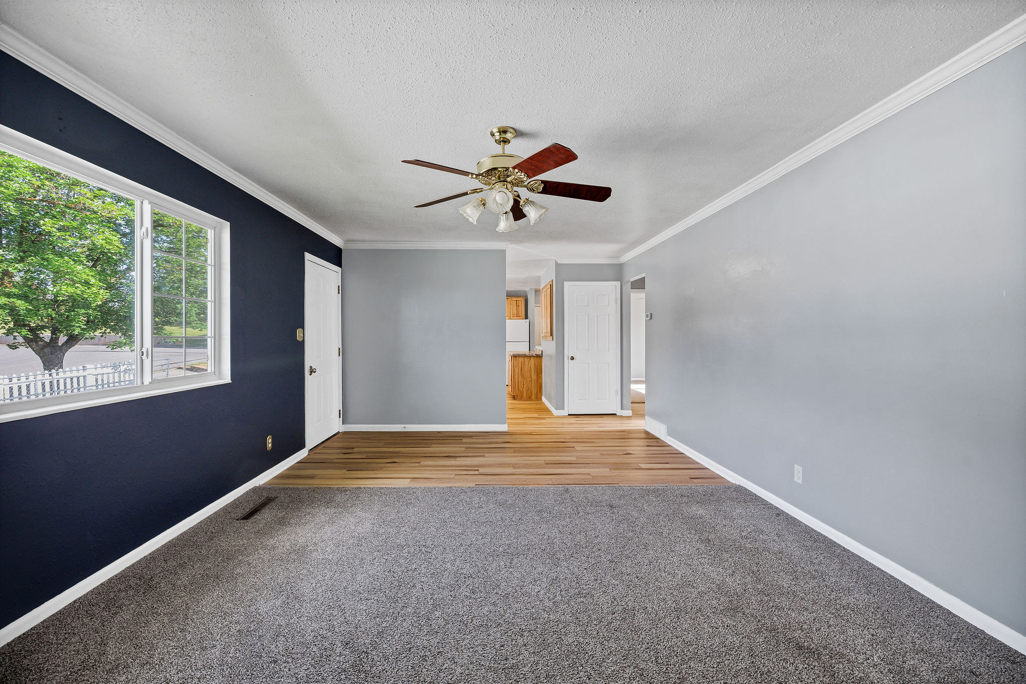 Spacious interior featuring a combination of wood-finish flooring and gray carpeting