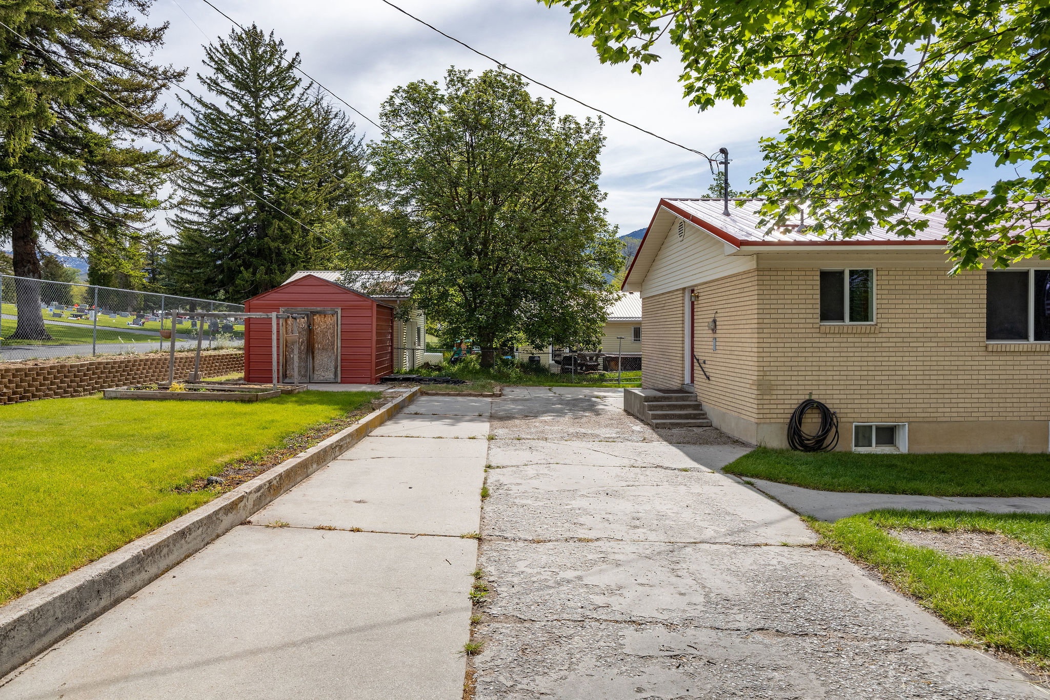 Exterior featuring brick siding, a red metal roof, and a detached red shed