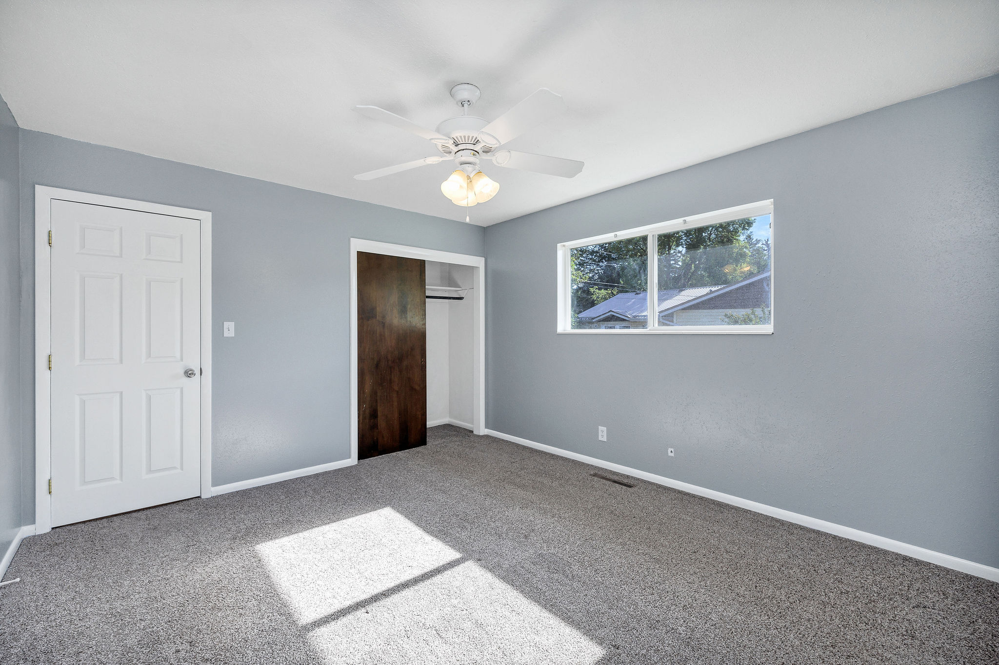 Bedroom featuring light gray walls, gray carpet, and a white ceiling fan with integrated lighting