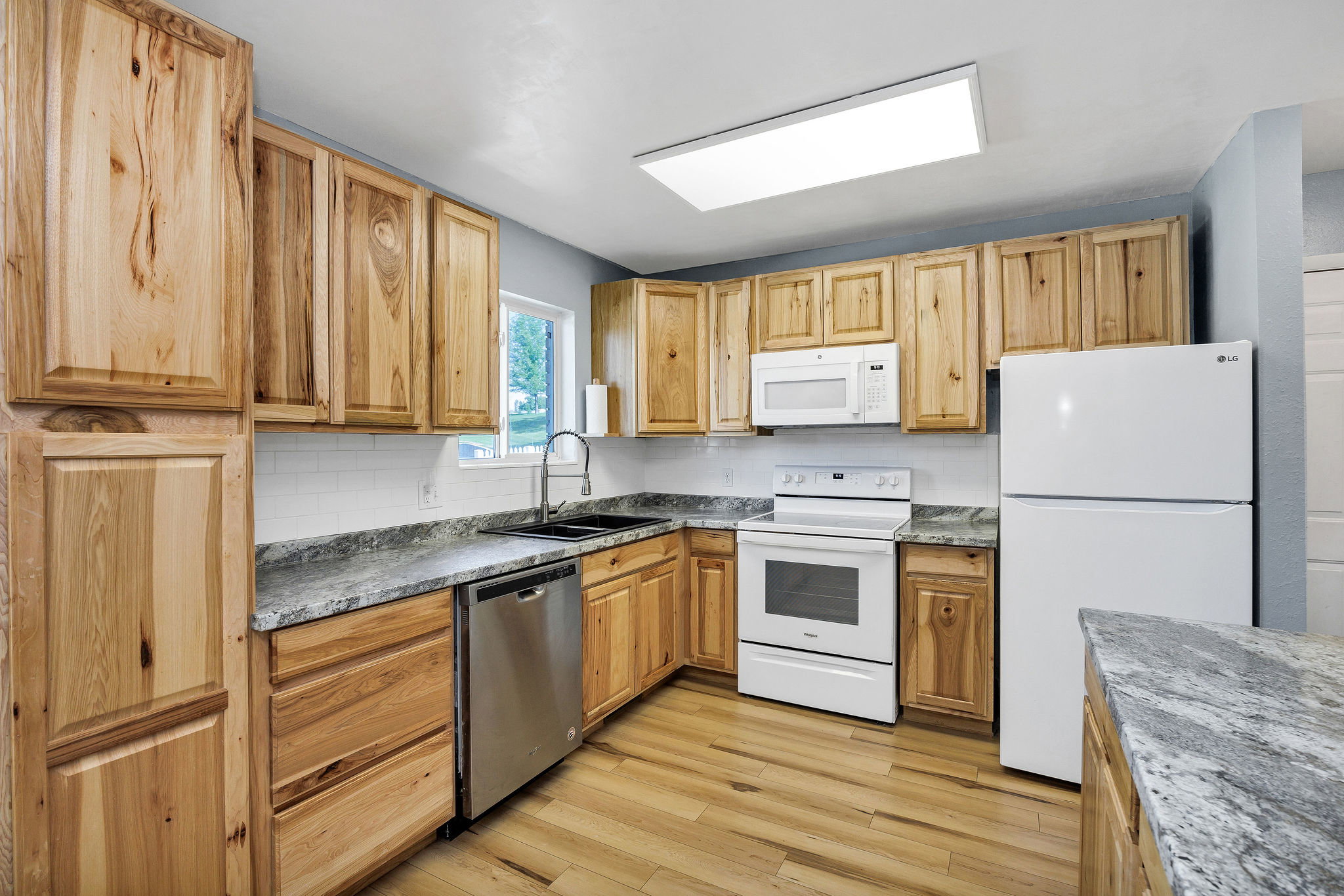 U-shaped kitchen featuring wood-finish cabinetry, granite-style countertops, and a white subway tile backsplash