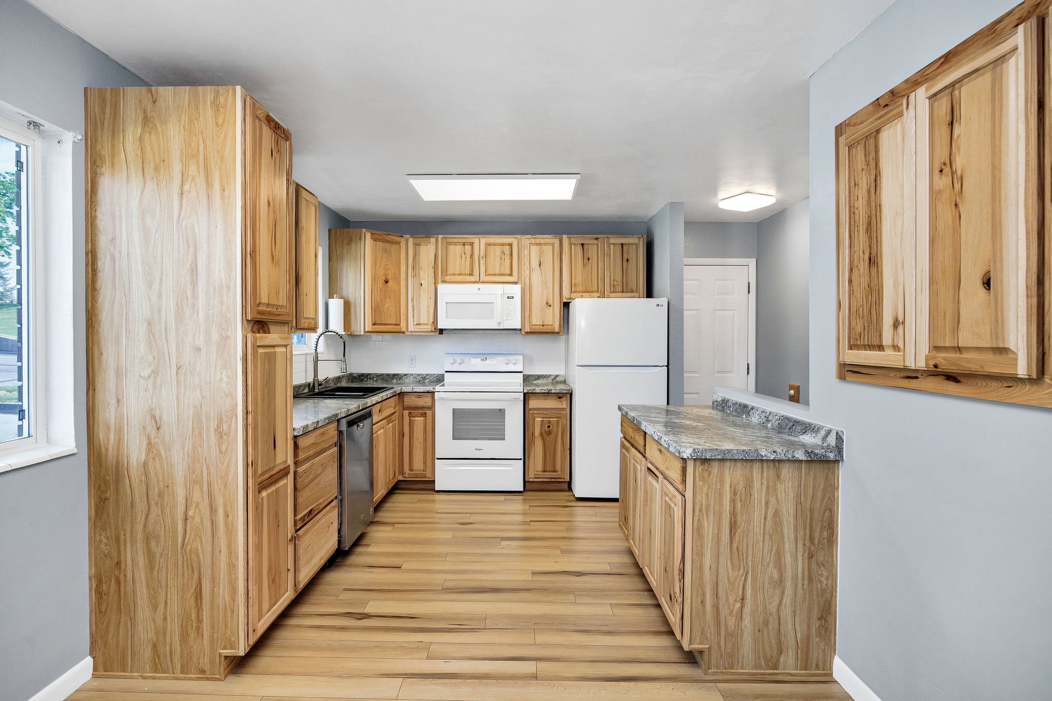 Kitchen featuring light wood-finish cabinetry, granite-style countertops, wood-finish flooring, white appliances, and recessed lighting