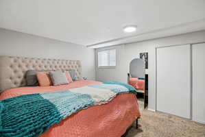 Bedroom featuring neutral wall paint, a window with blinds, carpeted flooring, and sliding closet doors