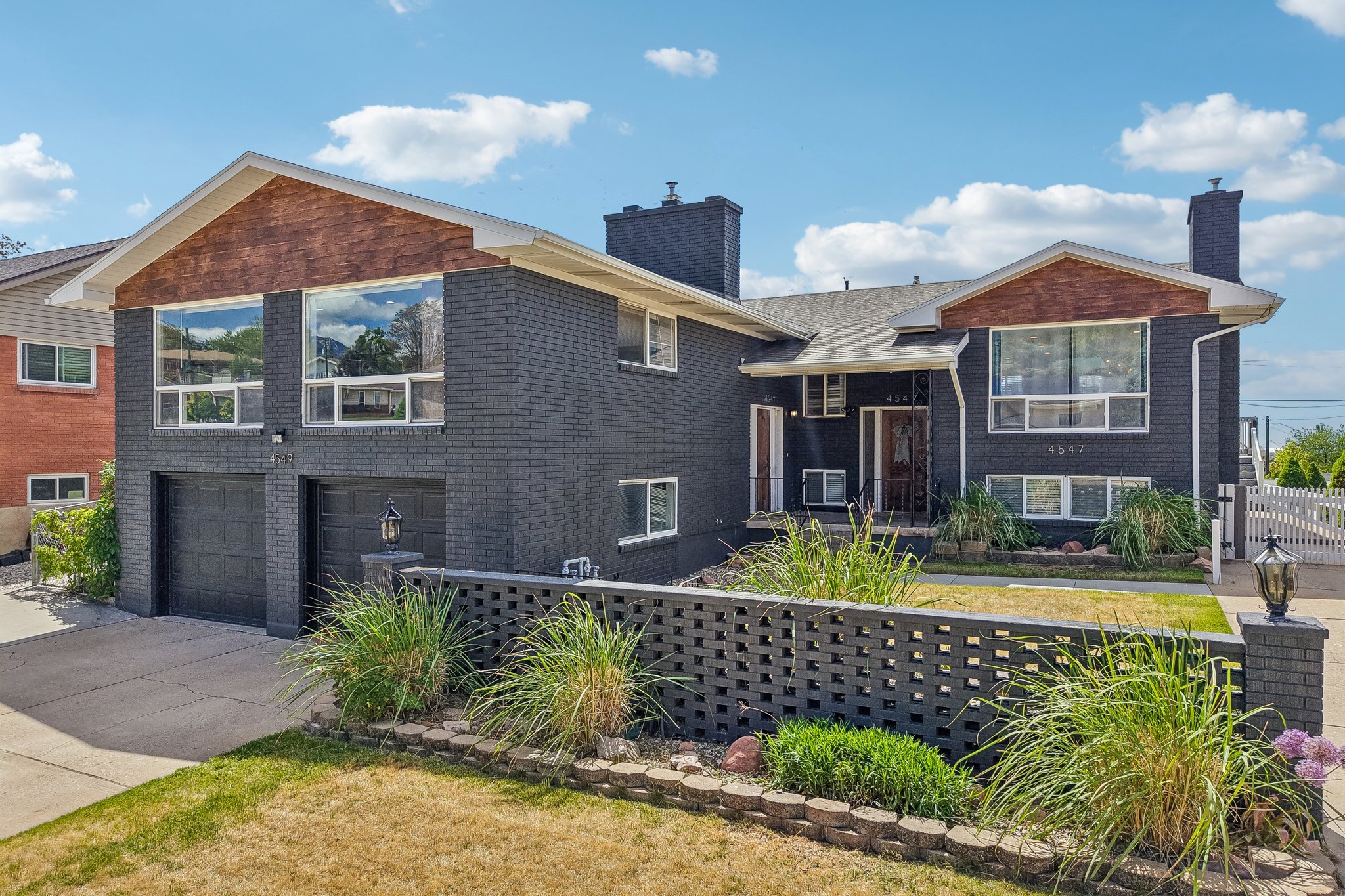Black brick exterior featuring wood-finish gables and a two-car garage