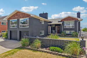 Black brick exterior featuring wood-finish gables and a two-car garage
