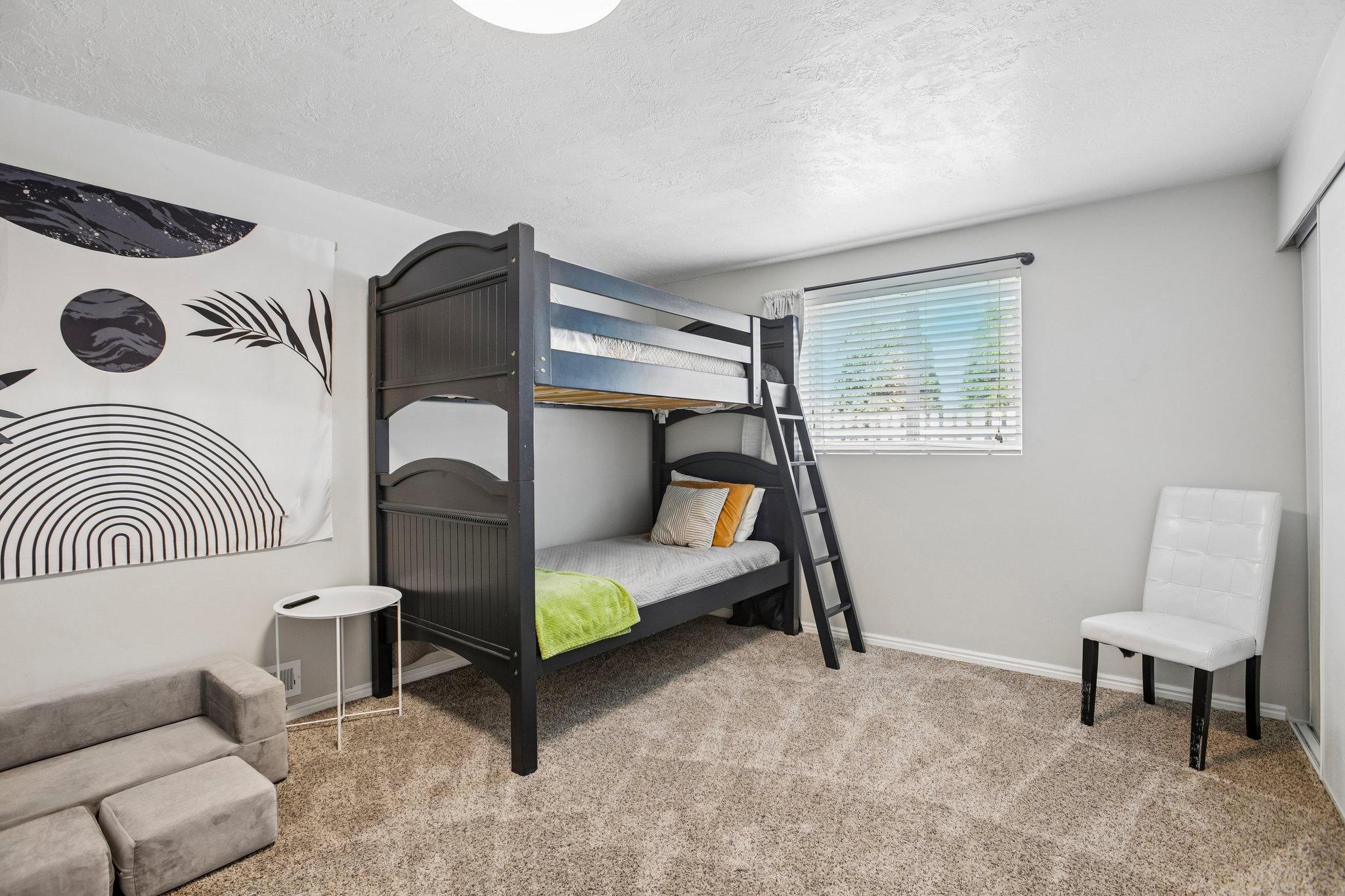 Carpeted room featuring a window with blinds, a built-in closet with sliding doors, and light gray painted walls
