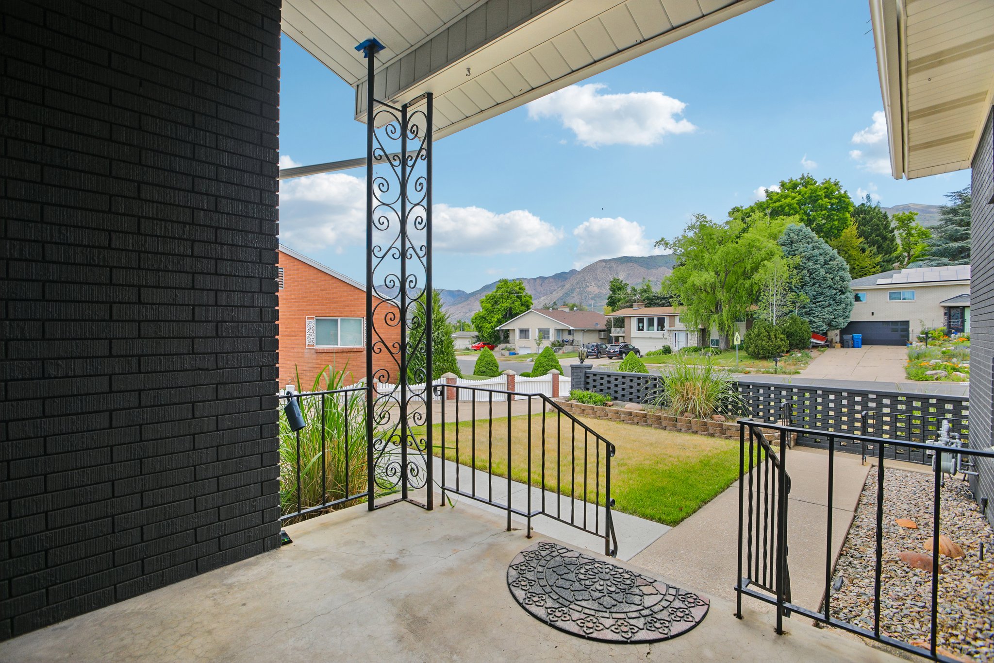 Front porch with black brick exterior and decorative wrought iron railings