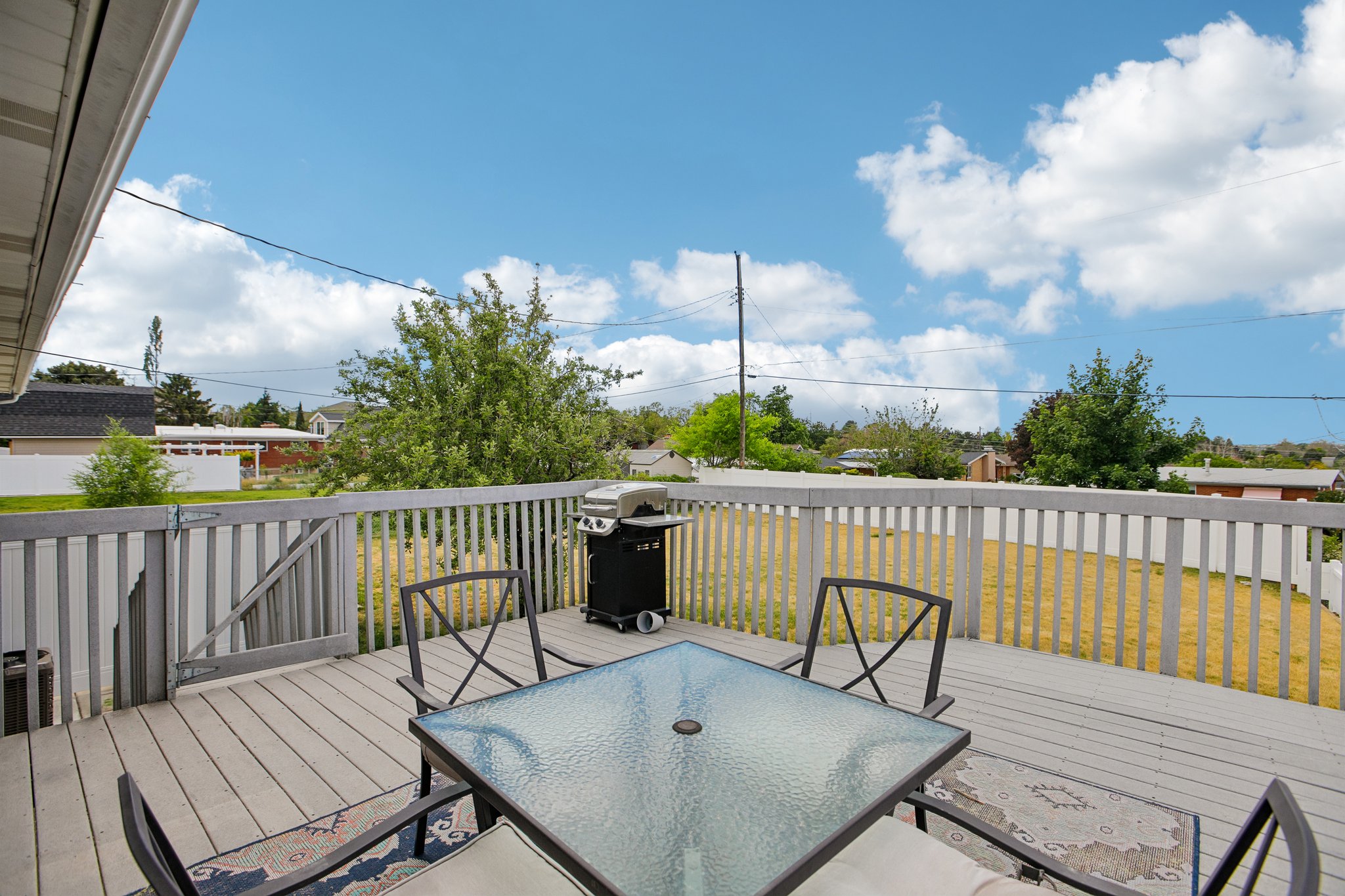 Spacious outdoor deck with wood-finish flooring and a white picket fence perimeter