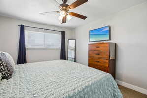Ceiling fan with light fixture, window with blinds and dark drapery rods, wall-mounted television, and light-toned wall paint