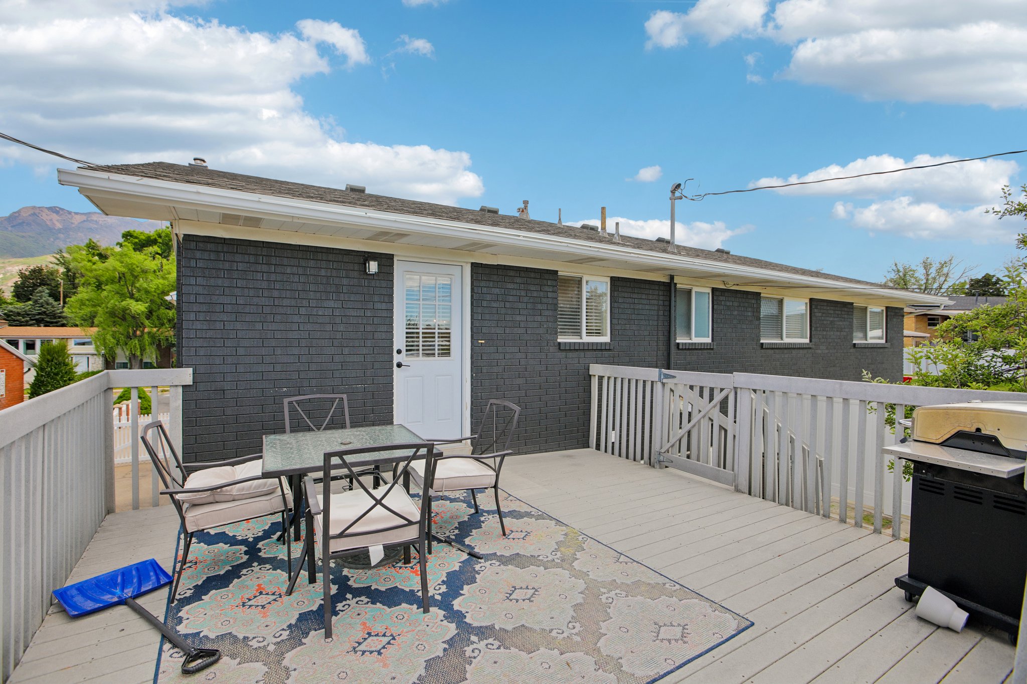 Exterior deck featuring a white railing system, dark brick siding, and multiple windows